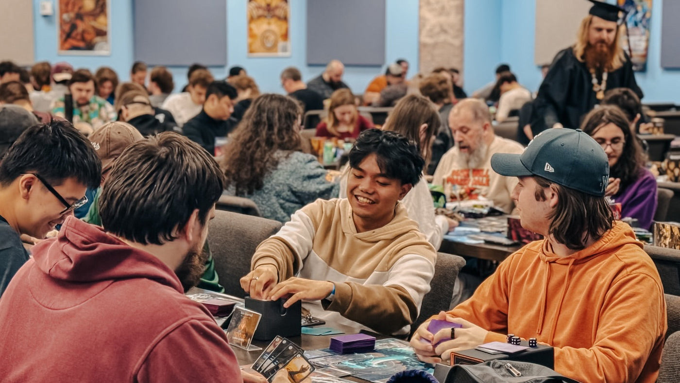 People playing card games in a casual setting with a crowd in the background